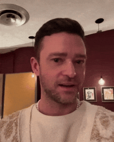 A Man With A Beard Is Wearing A White Sweater And A Pearl Necklace GIF
