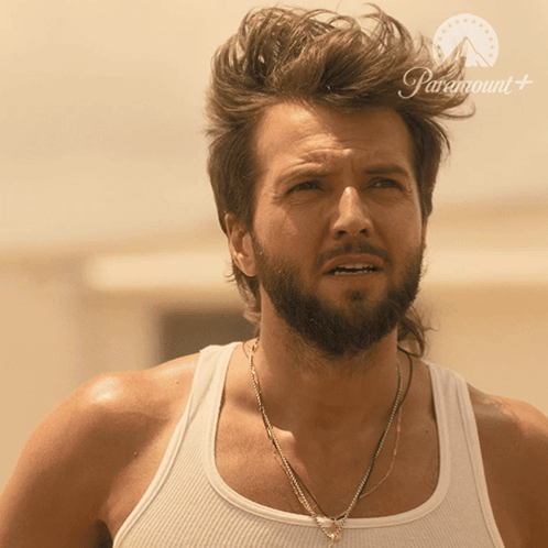A Man With A Beard Is Wearing A White Tank Top With Paramount Written On The Bottom GIF