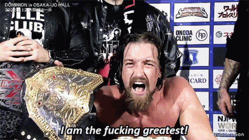 a man with a beard is wearing a wrestling belt and says i am the fucking greatest