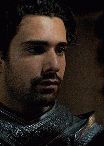 A Man With A Beard Is Wearing Armor And Looking At Something GIF