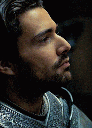 A Man With A Beard Is Wearing Armor And Looking Away From The Camera GIF