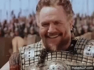 A Man With A Beard Is Wearing Armor And Smiling In Front Of A Crowd . GIF