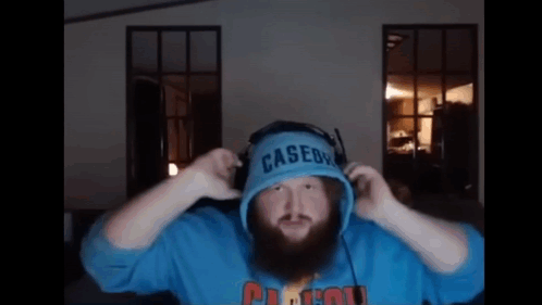 A Man With A Beard Is Wearing Headphones And A Blue Casedy Hoodie . GIF