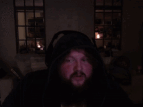 A Man With A Beard Is Wearing Headphones And A Hoodie GIF