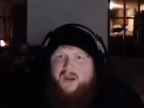 A Man With A Beard Is Wearing Headphones And Has The Words What Is That Supposed To Mean Above Him GIF