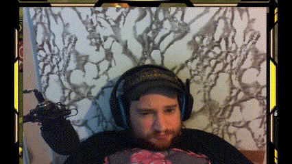 A Man With A Beard Is Wearing Headphones And Holding A Microphone While Sitting On A Bed GIF