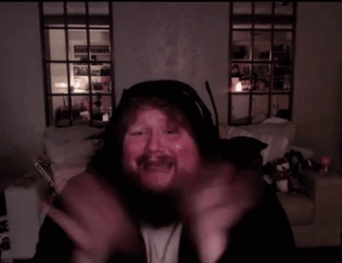 A Man With A Beard Is Wearing Headphones And Making A Face GIF