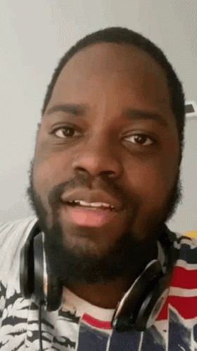 A Man With A Beard Is Wearing Headphones And Making A Face . GIF