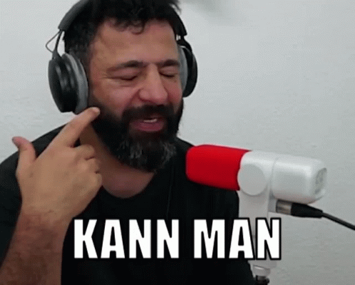 A Man With A Beard Is Wearing Headphones And Singing Into A Microphone While Saying Kann Man . GIF