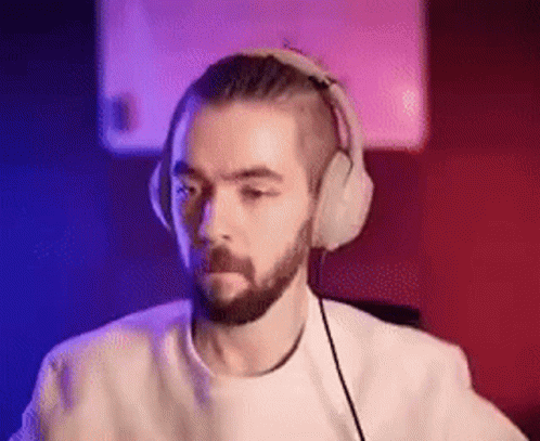 A Man With A Beard Is Wearing Headphones While Sitting In Front Of A Computer . GIF