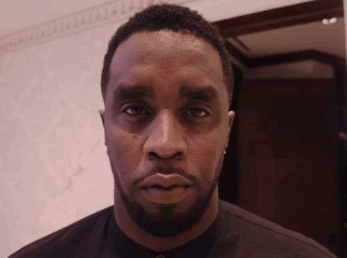 A Man With A Beard Looks At The Camera With A Serious Look On His Face GIF