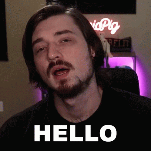 a man with a beard says hello in front of a pink sign