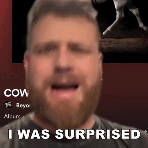 A Man With A Beard Says " I Was Surprised " In Front Of A Picture Of A Cow GIF