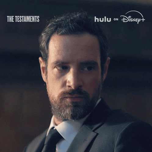 A Man With A Beard Says " Not Yet " In Front Of A Poster For The Testaments GIF