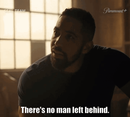 A Man With A Beard Says " There 'S No Man Left Behind " In A Dark Room GIF