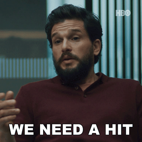 a man with a beard says " we need a hit " in white letters