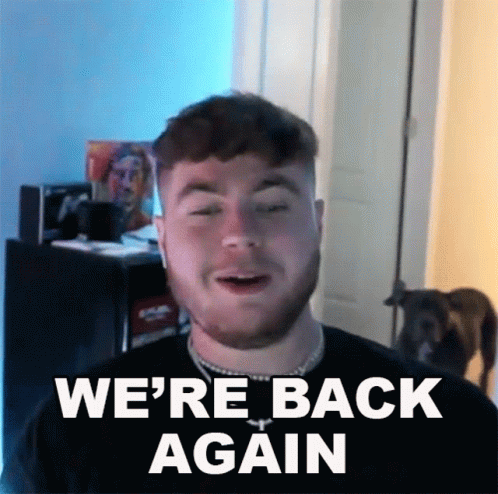 A Man With A Beard Says " We 'Re Back Again " In Front Of A Dog GIF