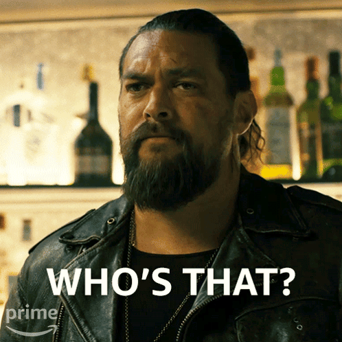 a man with a beard says who 's that in front of a bar