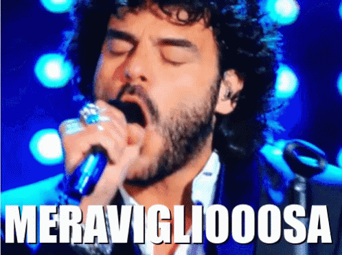 A Man With A Beard Singing Into A Microphone With The Word Meravigliaoosa Written Above Him GIF