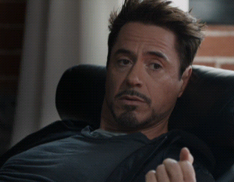 A Man With A Beard Sits In A Chair With His Hand Out GIF