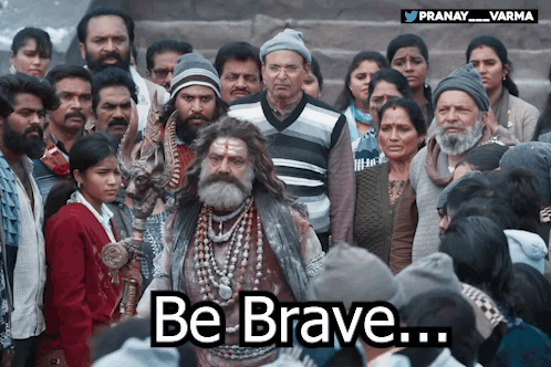 A Man With A Beard Stands In Front Of A Crowd With The Words Be Brave Written Below Him GIF
