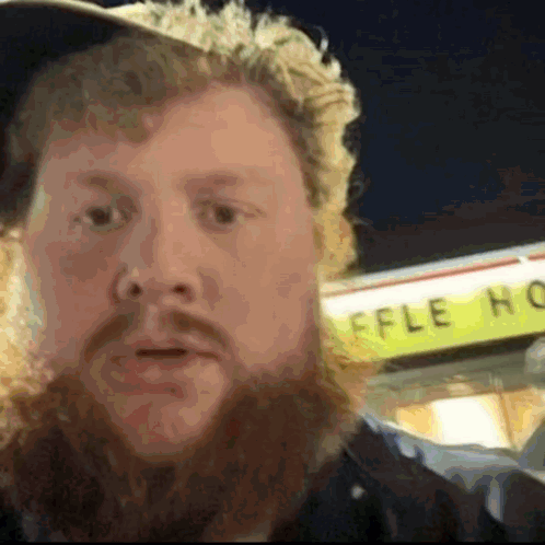 A Man With A Beard Stands In Front Of A Waffle House Sign GIF