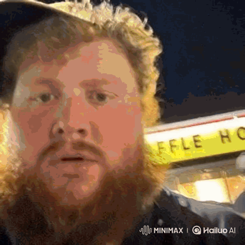 A Man With A Beard Stands In Front Of A Waffle House Sign GIF