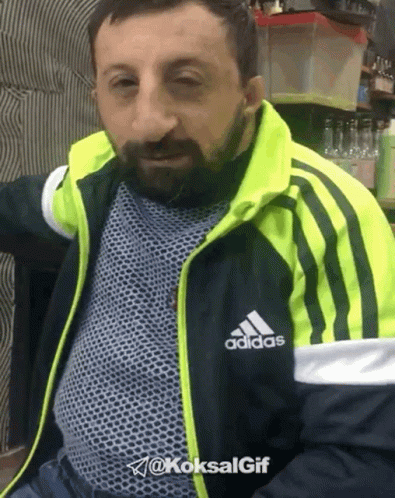 A Man With A Beard Wearing A Black And Yellow Adidas Jacket GIF