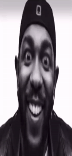 A Man With A Beard Wearing A Black Hat And A Black Jacket Is Smiling . GIF