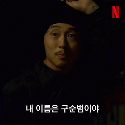 A Man With A Beard Wearing A Black Hat And A Black Jacket Is Talking In Korean . GIF