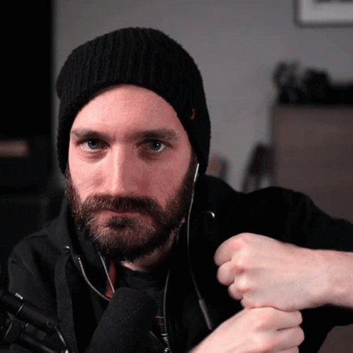 A Man With A Beard Wearing A Black Hat And Headphones GIF