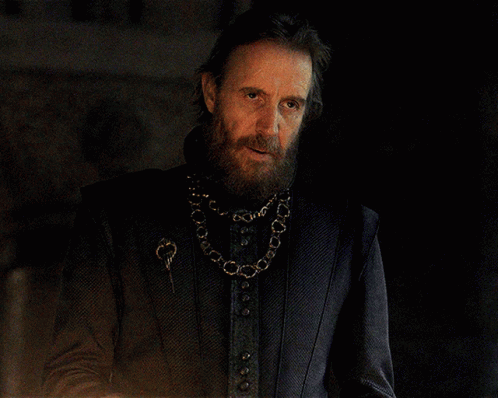 a man with a beard wearing a black jacket and a gold chain around his neck