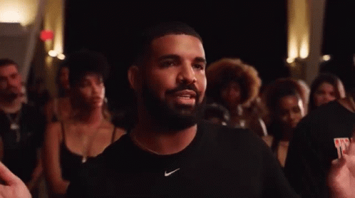 A Man With A Beard Wearing A Black Nike Shirt Is Standing In Front Of A Crowd . GIF