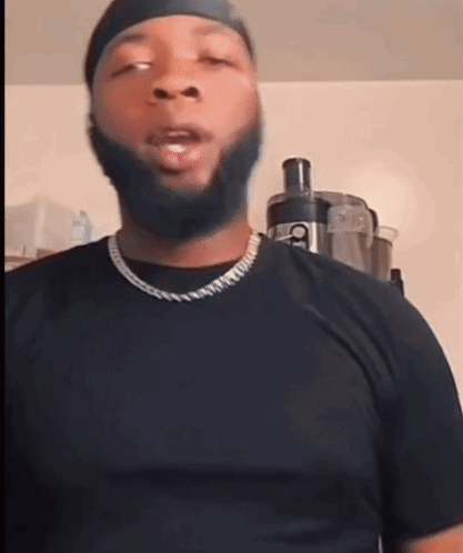 A Man With A Beard Wearing A Black Shirt And A Necklace GIF