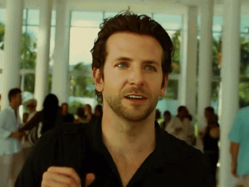 A Man With A Beard Wearing A Black Shirt Stands In Front Of A Crowd GIF