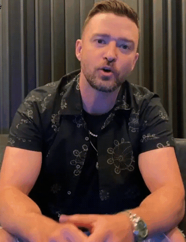 A Man With A Beard Wearing A Black Shirt With A Pattern Of Circles On It GIF