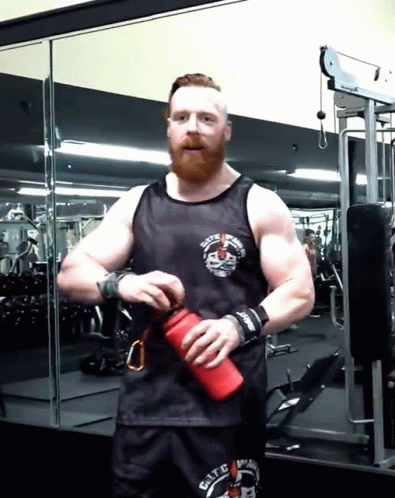 A Man With A Beard Wearing A Black Tank Top That Says ' Elite ' On The Front GIF