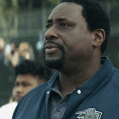 A Man With A Beard Wearing A Blue Jacket With A Lion On The Pocket GIF