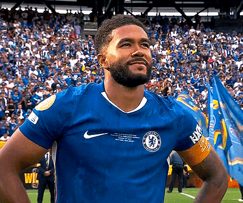 A Man With A Beard Wearing A Blue Nike Jersey Is Standing On A Soccer Field In Front Of A Crowd . GIF
