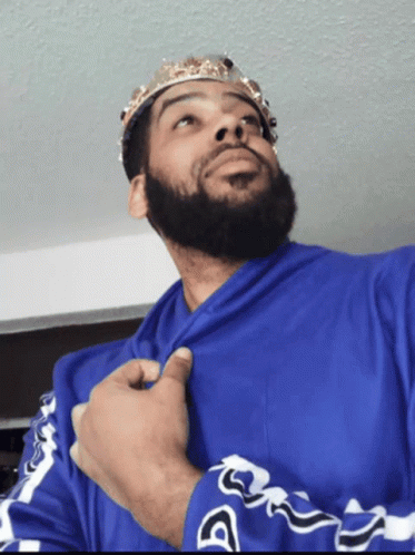 A Man With A Beard Wearing A Blue Shirt And A Crown On His Head GIF