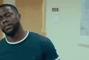 a man with a beard wearing a blue shirt is standing in a room with his eyes closed .