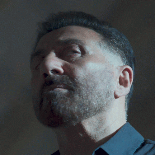 A Man With A Beard Wearing A Blue Shirt Looks At The Camera GIF