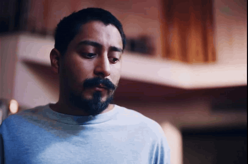 A Man With A Beard Wearing A Blue Shirt Looks Down GIF