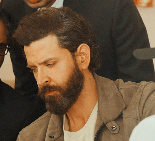 A Man With A Beard Wearing A Brown Jacket GIF