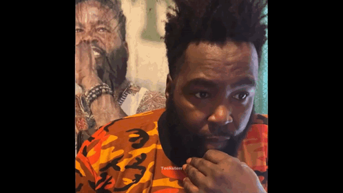 A Man With A Beard Wearing A Camouflage Shirt Looks At The Camera GIF