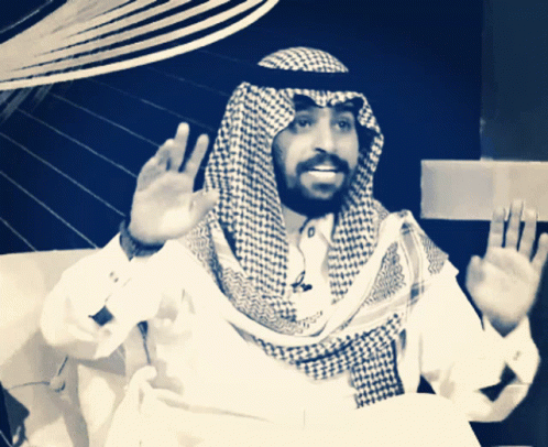a man with a beard wearing a checked scarf and a white shirt