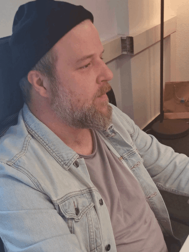 A Man With A Beard Wearing A Denim Jacket And A Black Beanie GIF