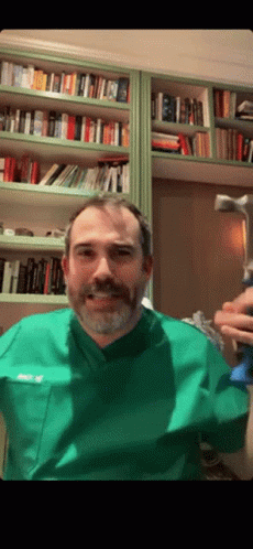 A Man With A Beard Wearing A Green Scrub Top With The Name Ricky On The Front Pocket GIF