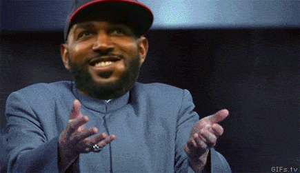 A Man With A Beard Wearing A Hat And A Blue Jacket Is Pointing At Something GIF