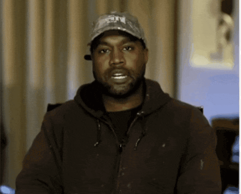 A Man With A Beard Wearing A Hat And A Jacket Looks At The Camera GIF